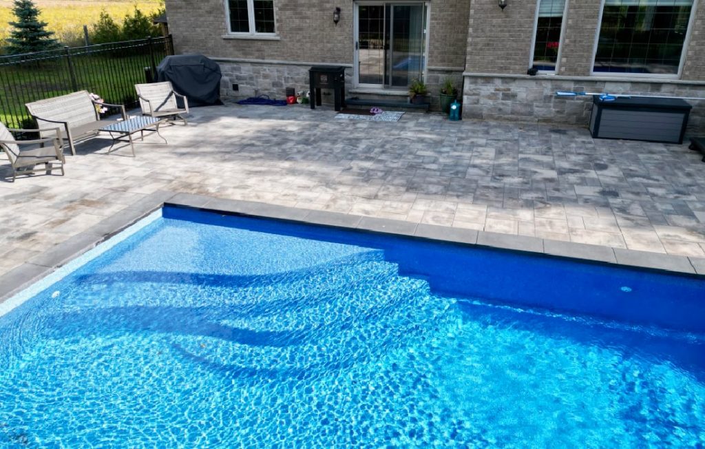 Fiberglass Pool showing step options with custom interlock patio by Boulder Design