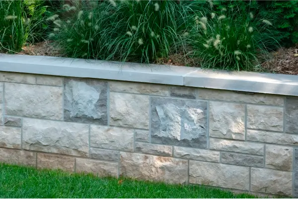 A backyard in Hamilton, Ontario with new patio and retaining wall by Boulder Design Pools and Landscapes