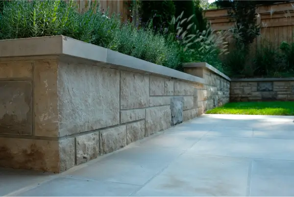 A backyard in Hamilton, Ontario with new patio and retaining wall by Boulder Design Pools and Landscapes