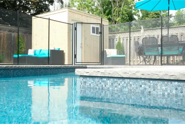 Backyard pool and landscape installation by Boulder Design Pools & Landscapes with pool barrier safety fence, turf grass and waterfall feature