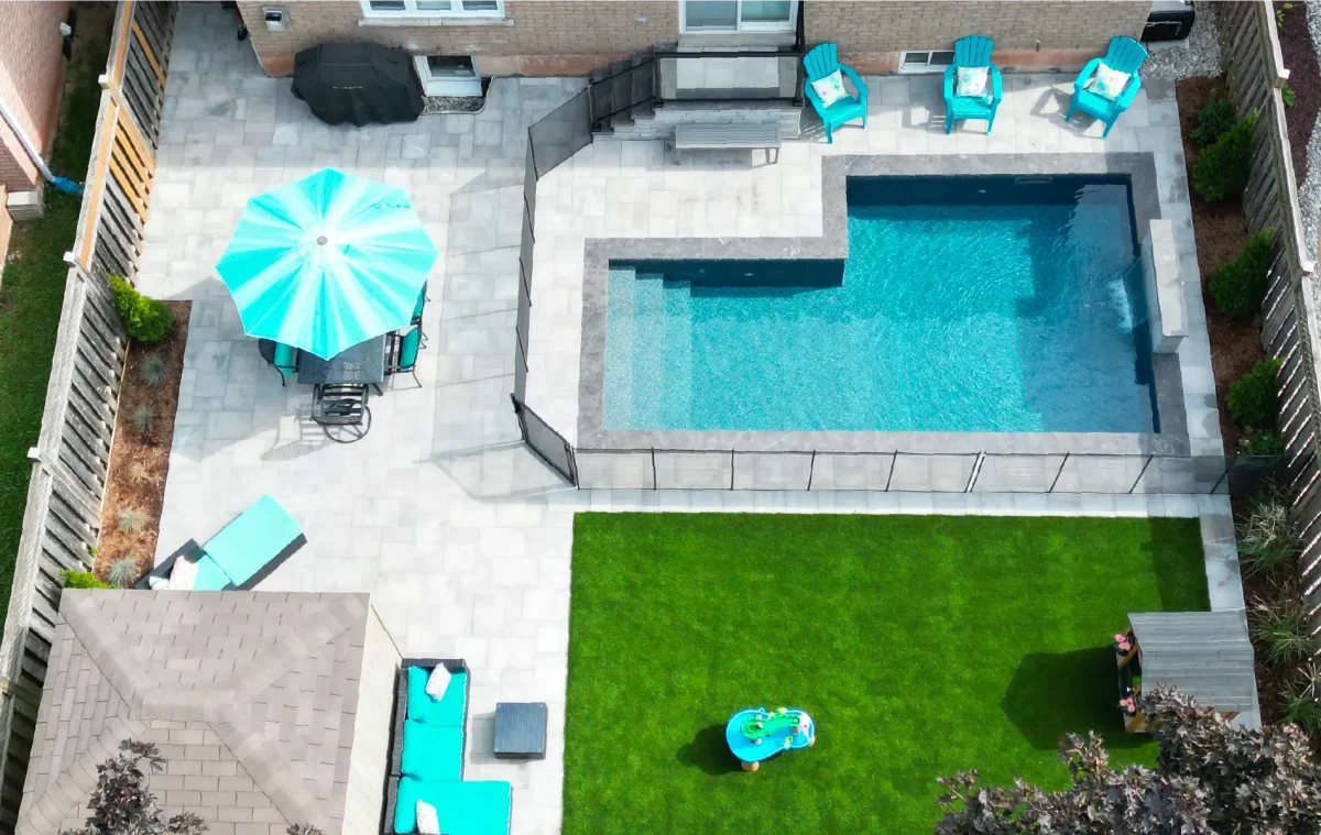 Backyard pool and landscape installation by Boulder Design Pools & Landscapes with pool barrier safety fence, turf grass and waterfall feature