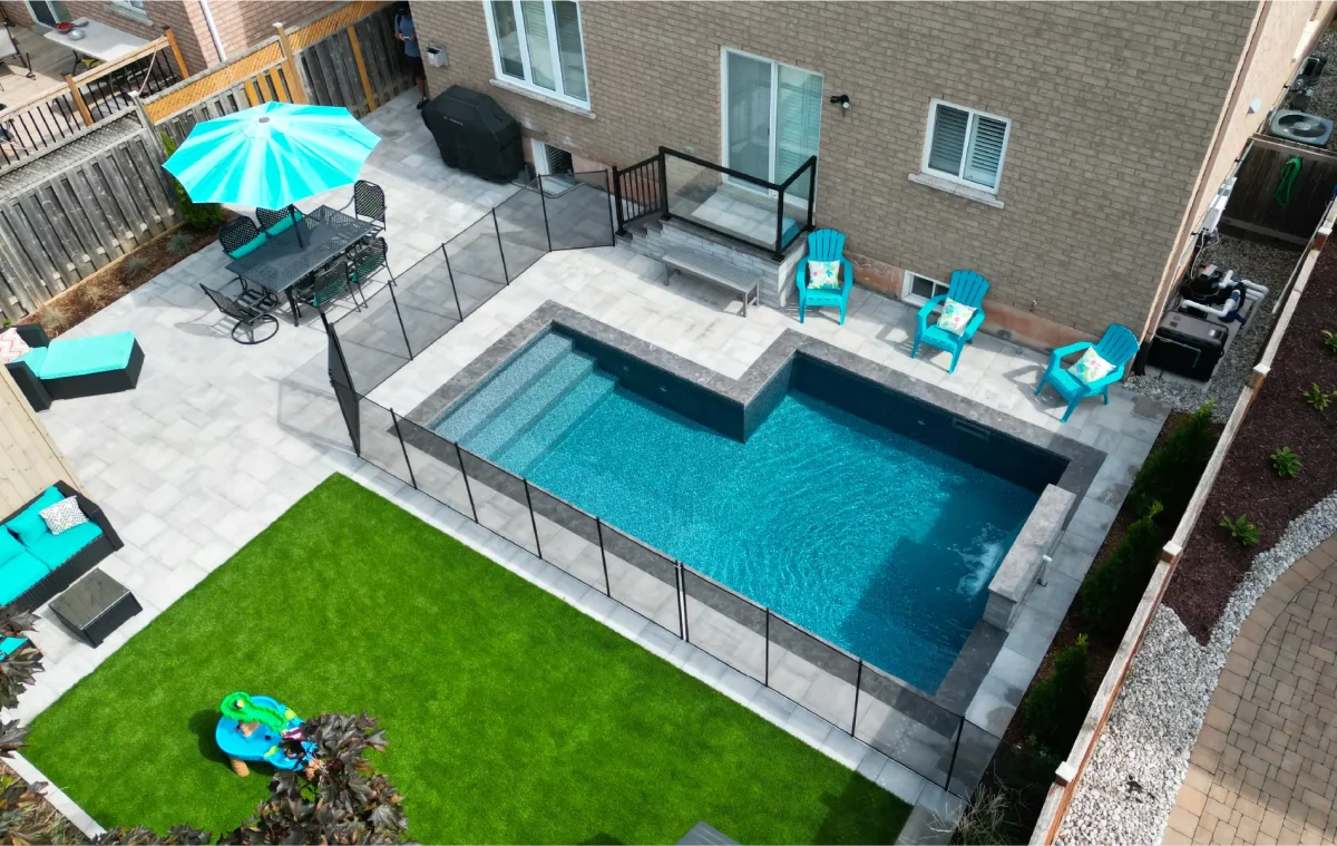 Backyard pool and landscape installation by Boulder Design Pools & Landscapes with pool barrier safety fence, turf grass and waterfall feature