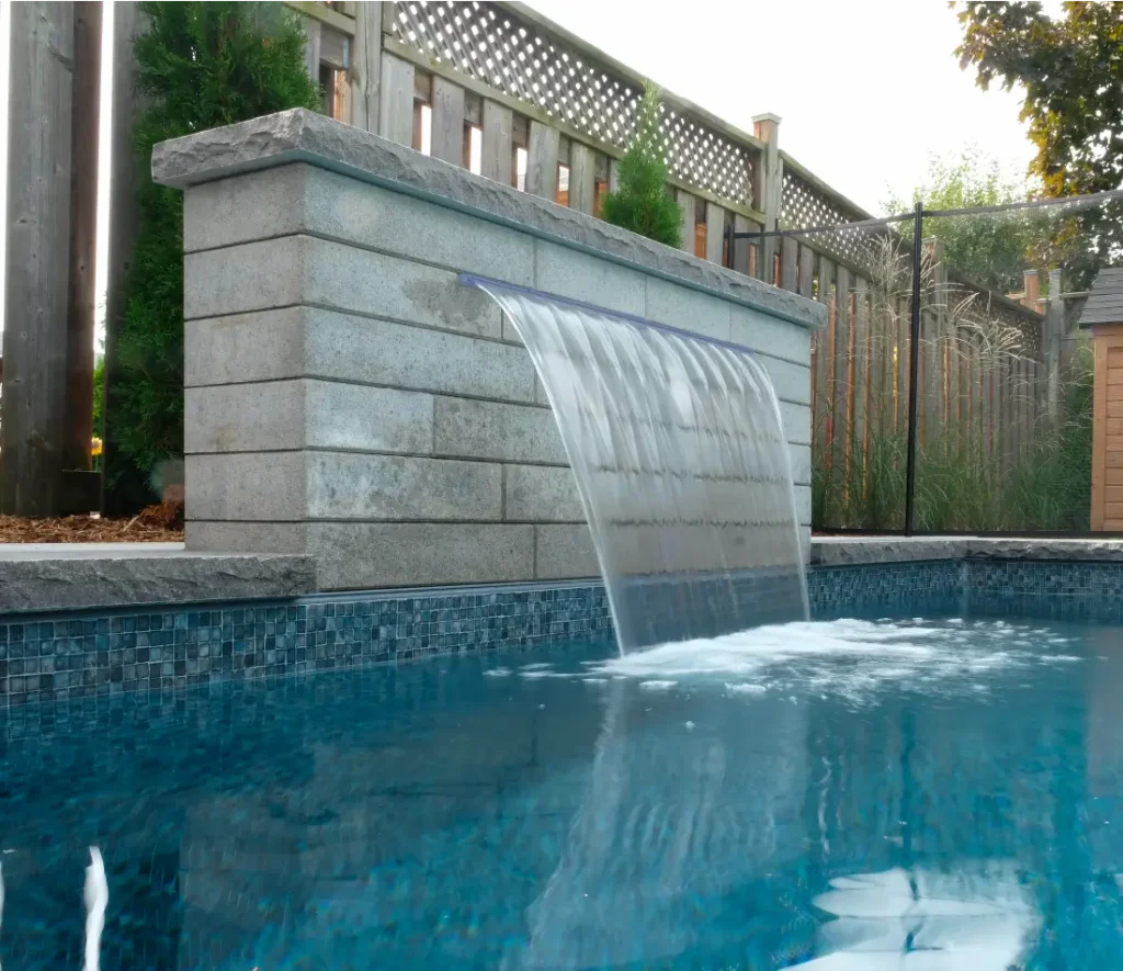 Backyard pool and landscape installation by Boulder Design Pools & Landscapes with pool barrier safety fence, turf grass and waterfall feature