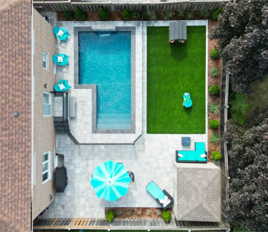 Backyard pool and landscape installation by Boulder Design Pools & Landscapes with pool barrier safety fence, turf grass and waterfall feature