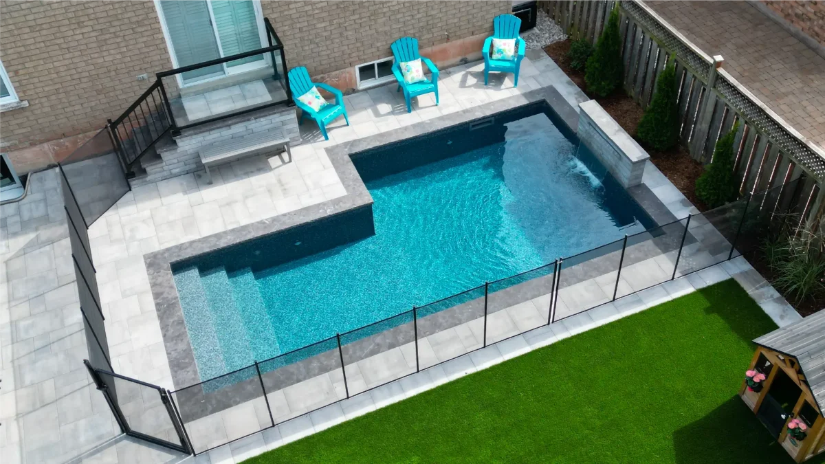 Backyard pool and landscape installation by Boulder Design Pools & Landscapes with pool barrier safety fence, turf grass and waterfall feature